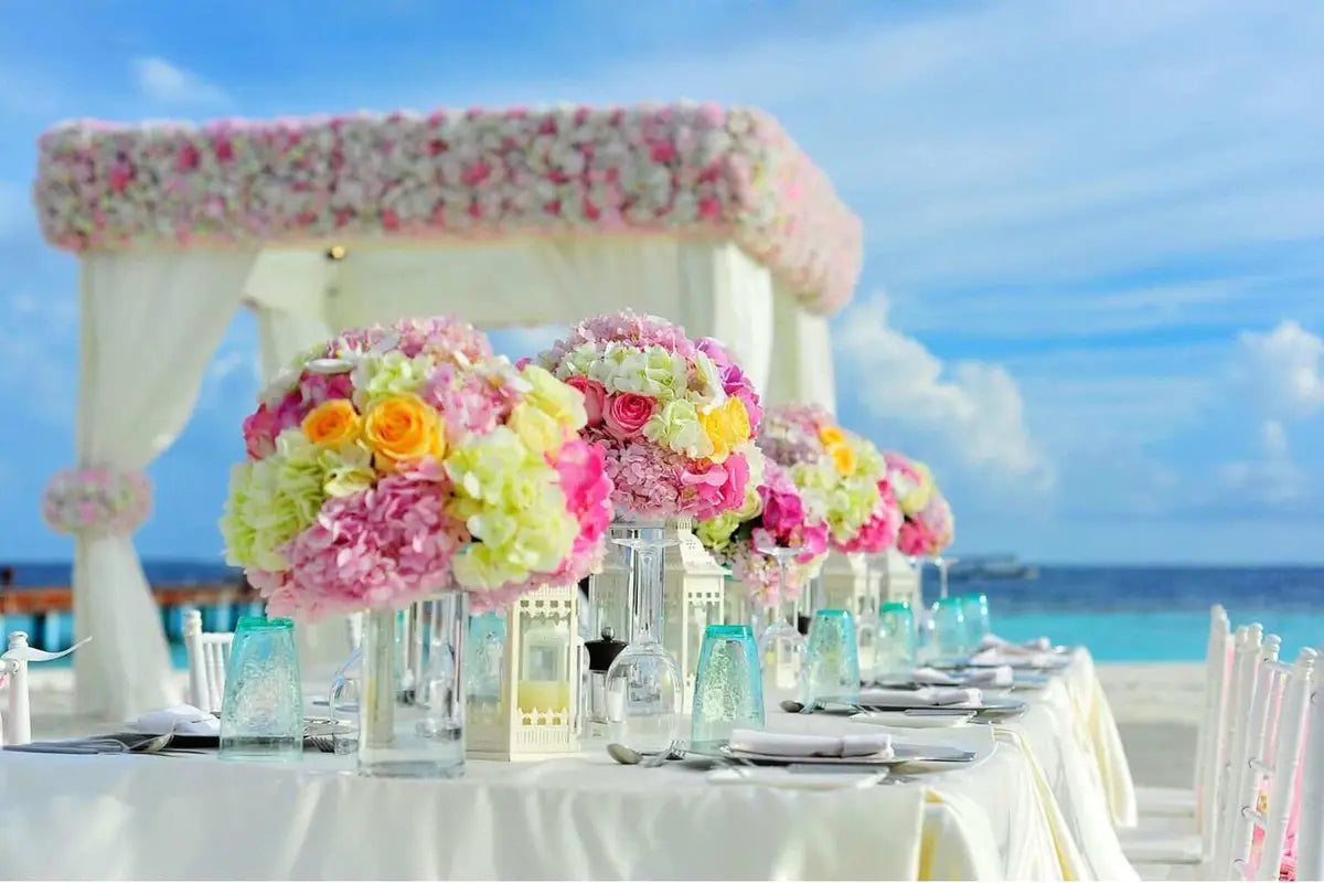 A row of flower balls on a table beside a mantled arch by the sea