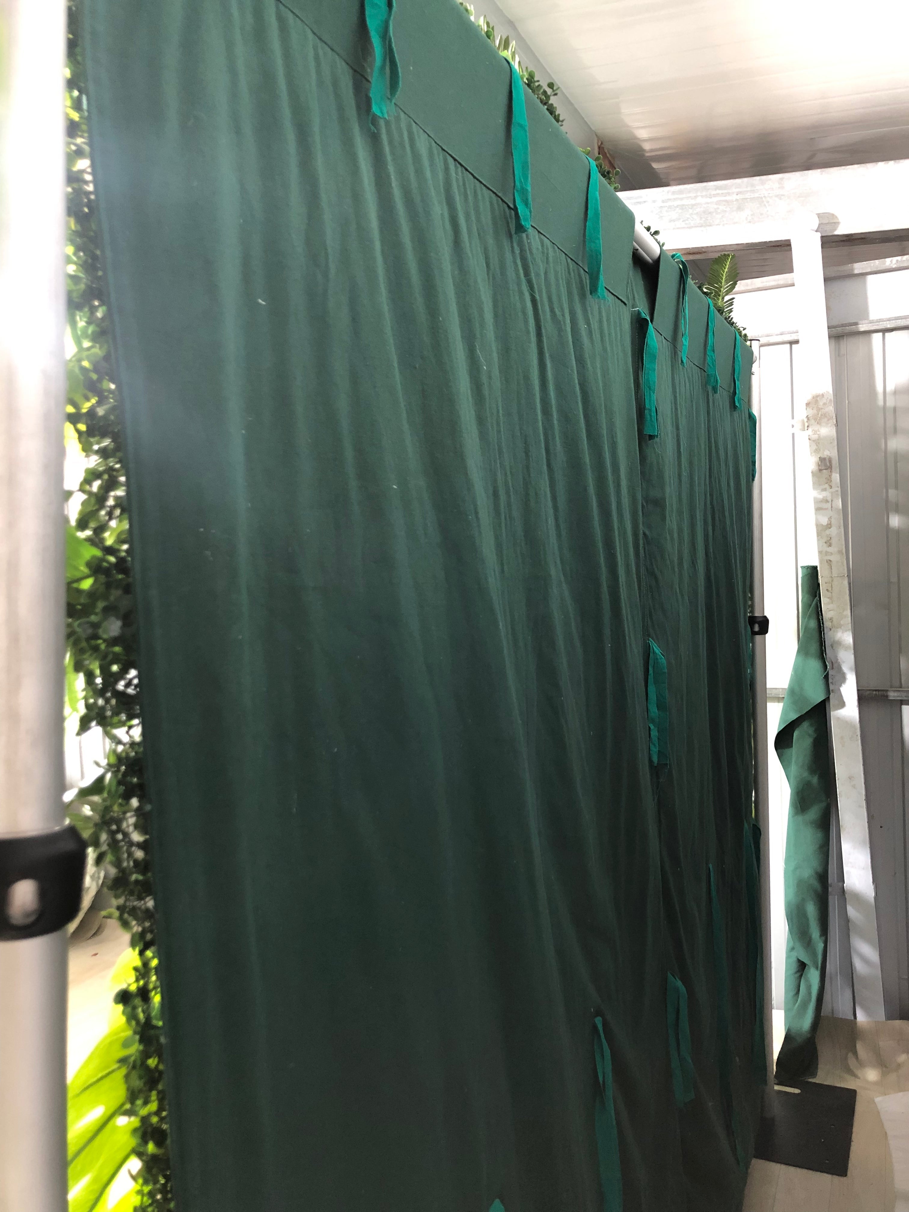 The green tropical leaves flower wall is fixed to a green cloth.