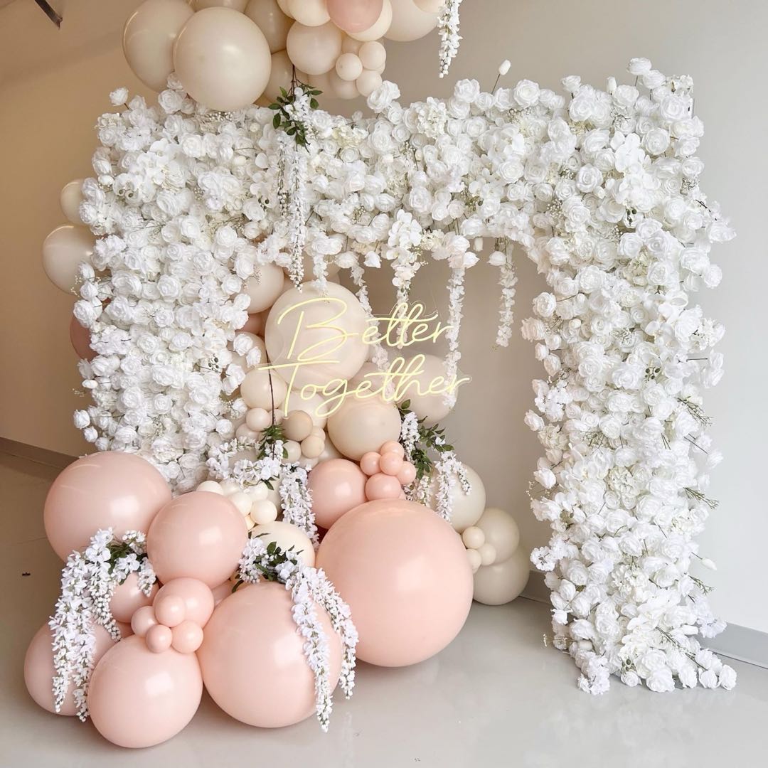 Balloon decor complements white flower arch, offering a beautiful and festive backdrop.